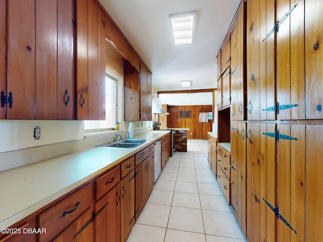 kitchen featuring stainless steel appliances, sink, light tile patterned floors, and wooden walls