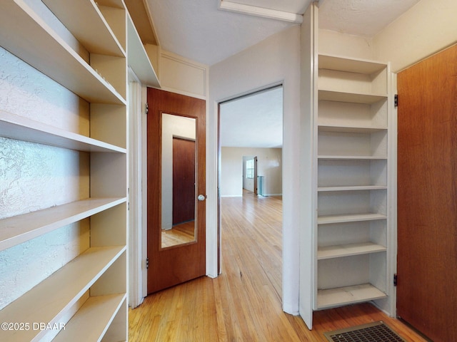 walk in closet with light hardwood / wood-style floors