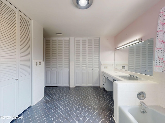 bathroom with vanity, a bath, and tile patterned floors