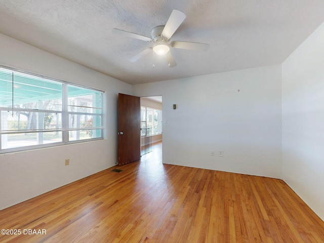 unfurnished room with ceiling fan, light hardwood / wood-style floors, and a textured ceiling