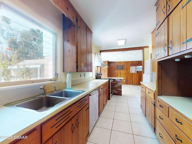 kitchen featuring sink, light tile patterned floors, appliances with stainless steel finishes, wooden walls, and exhaust hood