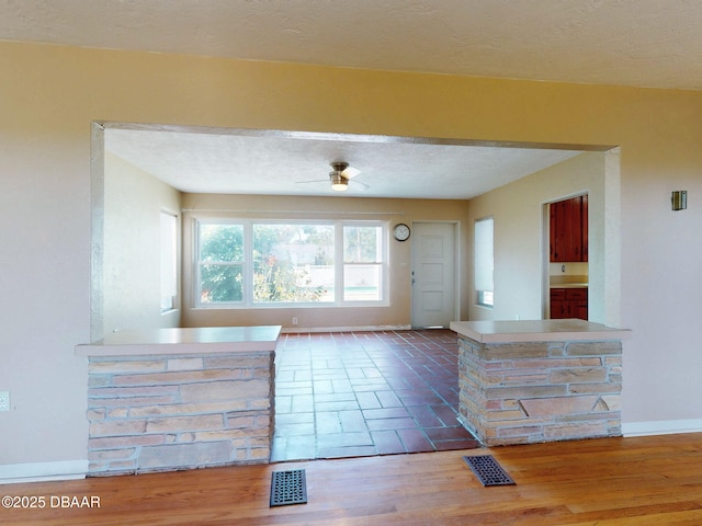 entryway with a textured ceiling, wood-type flooring, and ceiling fan