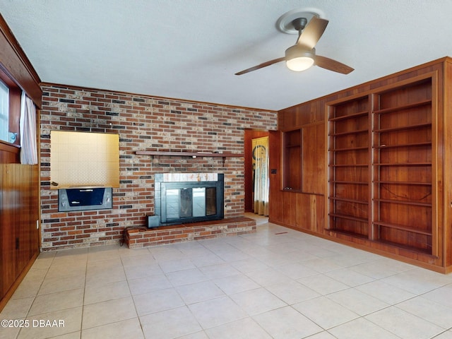 unfurnished living room with brick wall, a brick fireplace, a textured ceiling, and built in shelves