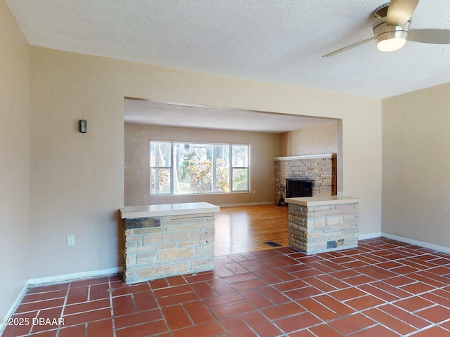 unfurnished living room featuring a textured ceiling, a fireplace, and ceiling fan