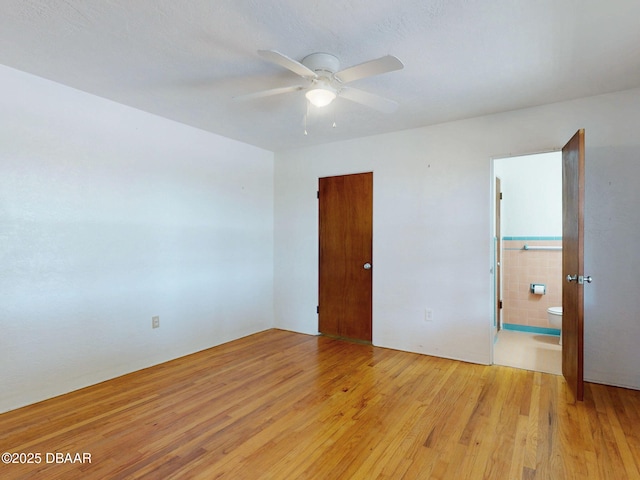 empty room with ceiling fan and light hardwood / wood-style flooring