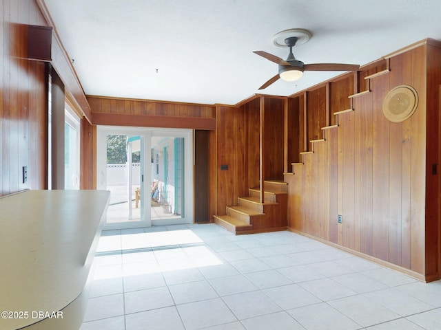 stairway featuring wooden walls, tile patterned floors, french doors, and ceiling fan