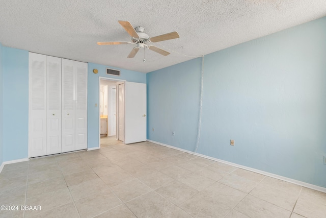 unfurnished bedroom featuring ceiling fan, light tile patterned floors, a textured ceiling, and a closet