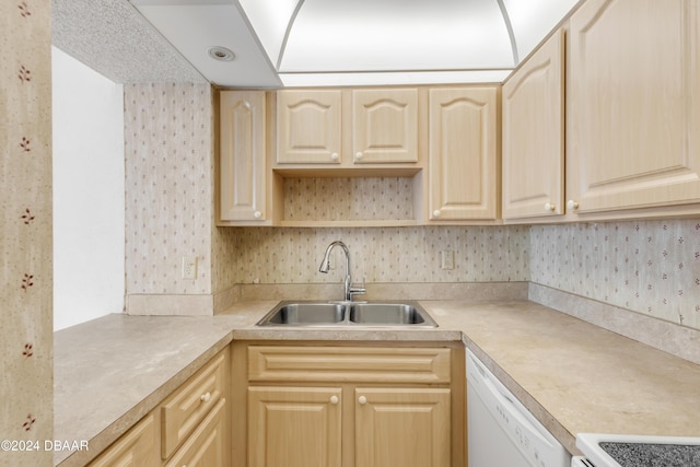 kitchen with white dishwasher, light brown cabinets, range, and sink