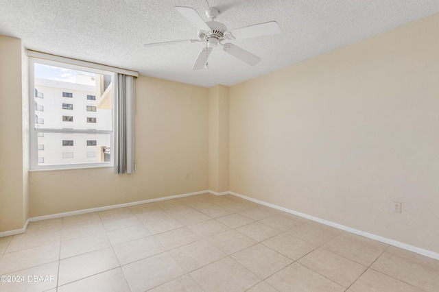 empty room with a textured ceiling, ceiling fan, and light tile patterned flooring