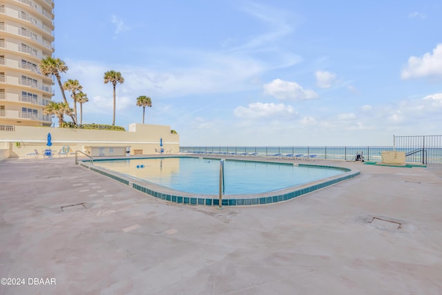 view of pool featuring a water view and a patio area