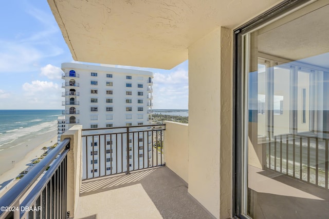 balcony with a water view and a view of the beach