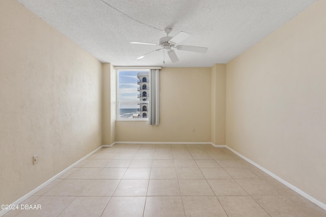 spare room featuring light tile patterned floors, a textured ceiling, and ceiling fan