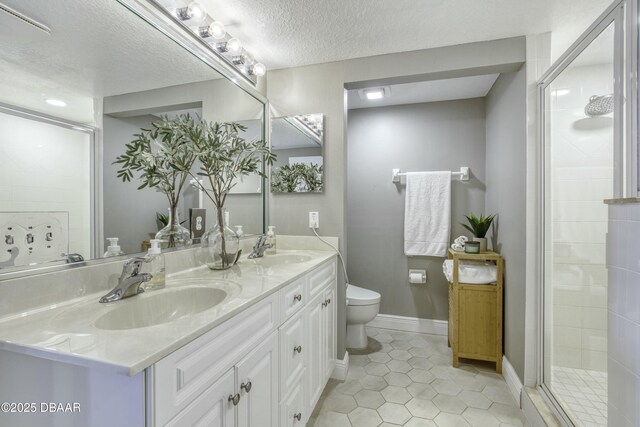 bathroom with vanity, a textured ceiling, a shower with shower door, tile patterned floors, and toilet