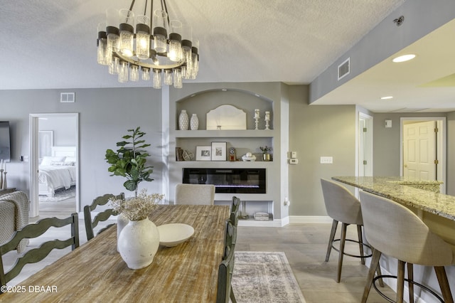 dining area with a notable chandelier, hardwood / wood-style floors, built in features, and a textured ceiling