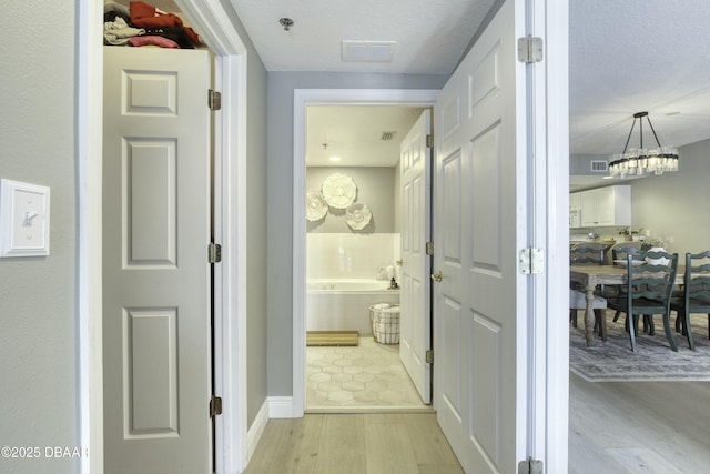 hall featuring a textured ceiling and light hardwood / wood-style flooring