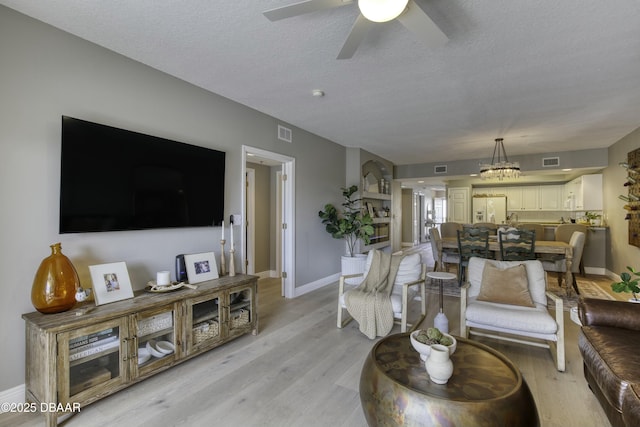 living room featuring ceiling fan, a textured ceiling, and light wood-type flooring