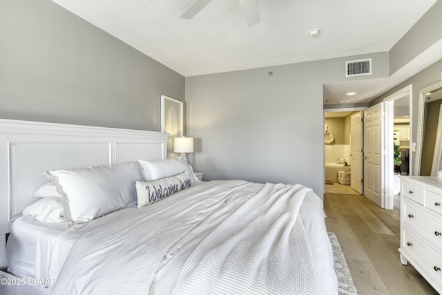 bedroom featuring ceiling fan, ensuite bathroom, and light wood-type flooring