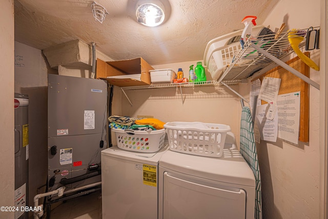 washroom with electric water heater, heating unit, a textured ceiling, and washing machine and clothes dryer