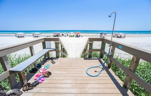 wooden deck with a beach view and a water view