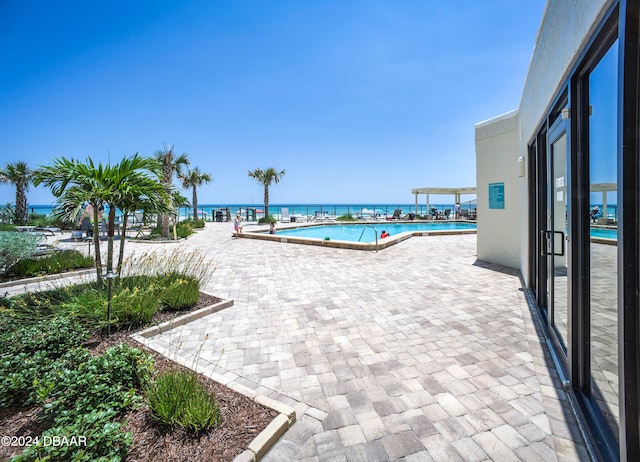 view of swimming pool with a water view and a patio area