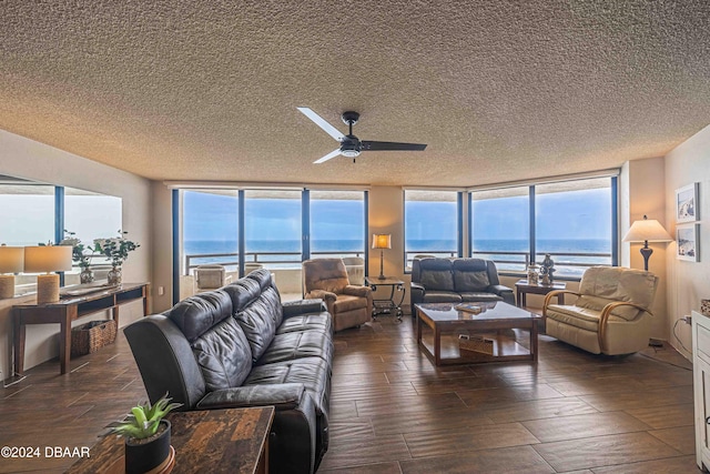 living room with a textured ceiling, a water view, and a healthy amount of sunlight