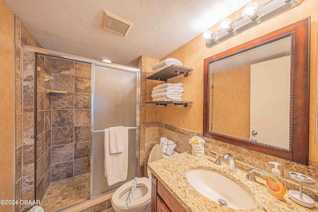 bathroom featuring vanity, a shower with door, a textured ceiling, and toilet