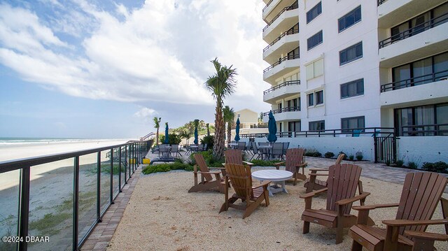 view of patio with a water view, a beach view, and a balcony