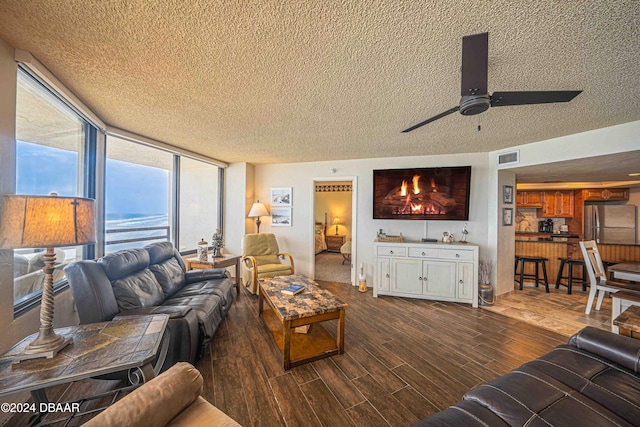 living room featuring expansive windows, wood-type flooring, ceiling fan, and a textured ceiling