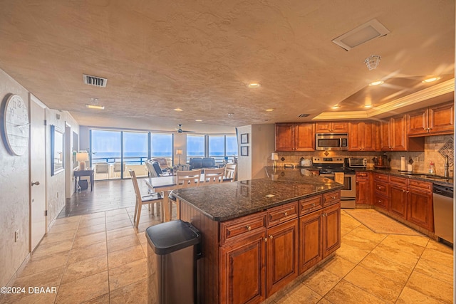 kitchen with stainless steel appliances, a center island, sink, tasteful backsplash, and dark stone countertops