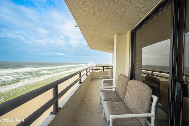 balcony featuring a water view and a beach view