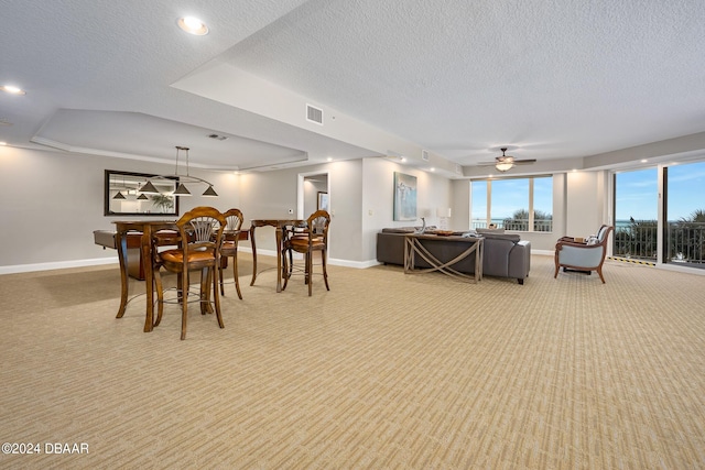 carpeted dining area with a tray ceiling, a textured ceiling, ceiling fan, and crown molding