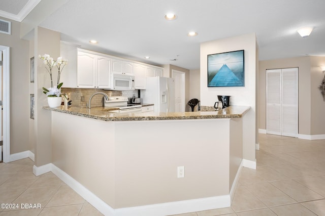 kitchen with kitchen peninsula, light stone countertops, backsplash, white appliances, and white cabinets