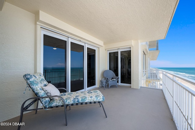 balcony featuring a view of the beach and a water view