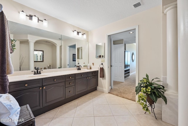 bathroom with vanity, tile patterned flooring, a textured ceiling, and ornate columns