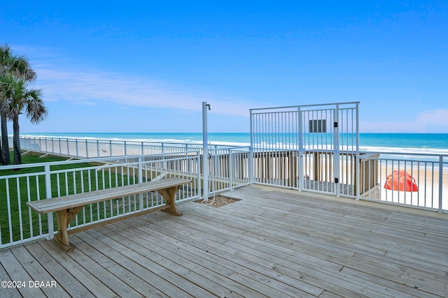 deck with a view of the beach, a water view, and a lawn