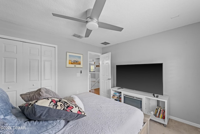 bedroom featuring a closet, a textured ceiling, light carpet, and ceiling fan