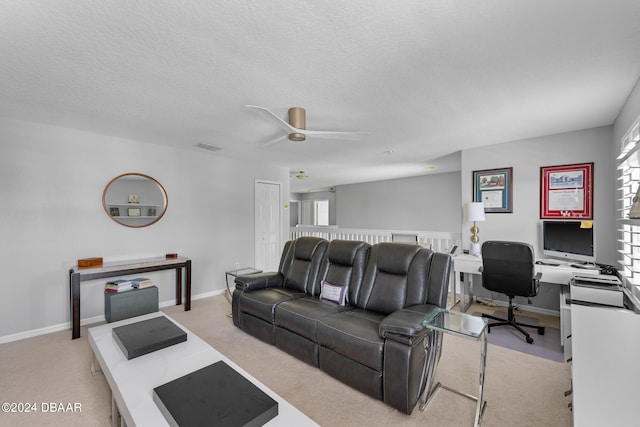 living room featuring ceiling fan, light colored carpet, and a textured ceiling