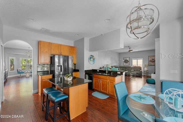 kitchen with sink, a center island, stainless steel fridge, dark hardwood / wood-style flooring, and black dishwasher