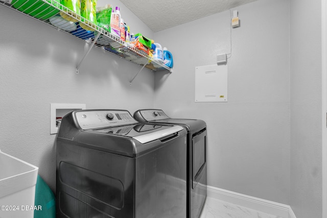 clothes washing area featuring a textured ceiling, washer and clothes dryer, and sink