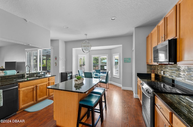 kitchen with sink, appliances with stainless steel finishes, a kitchen breakfast bar, a center island, and dark hardwood / wood-style flooring