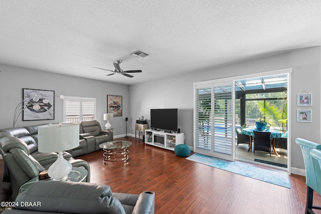 living room with dark wood-type flooring, ceiling fan, and a healthy amount of sunlight