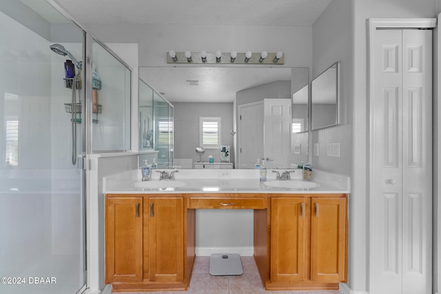 bathroom with vanity, a textured ceiling, tile patterned flooring, and a shower with door