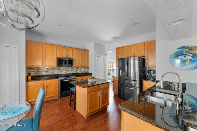 kitchen with stainless steel appliances, sink, dark hardwood / wood-style floors, a textured ceiling, and a center island