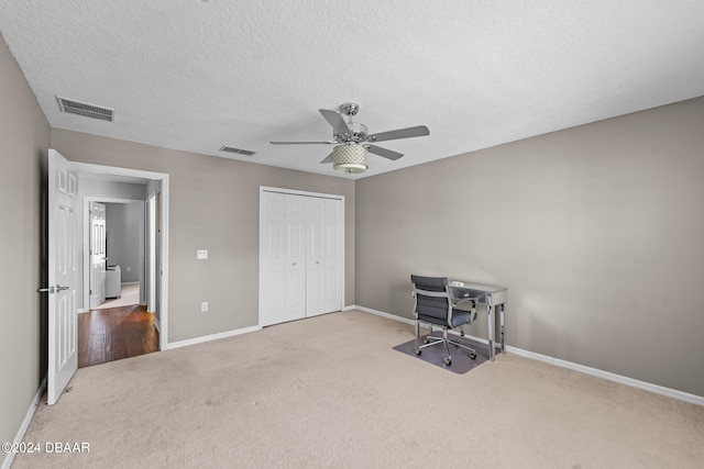 unfurnished office featuring carpet, a textured ceiling, and ceiling fan