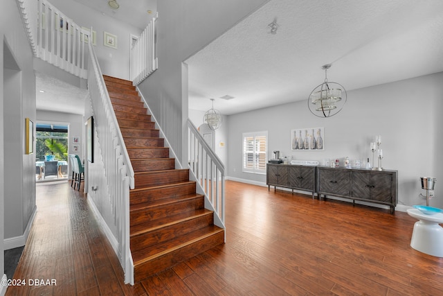 staircase featuring hardwood / wood-style flooring, a wealth of natural light, and a notable chandelier