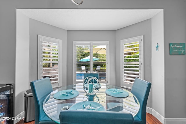 dining space featuring a textured ceiling, a wealth of natural light, hardwood / wood-style flooring, and beverage cooler