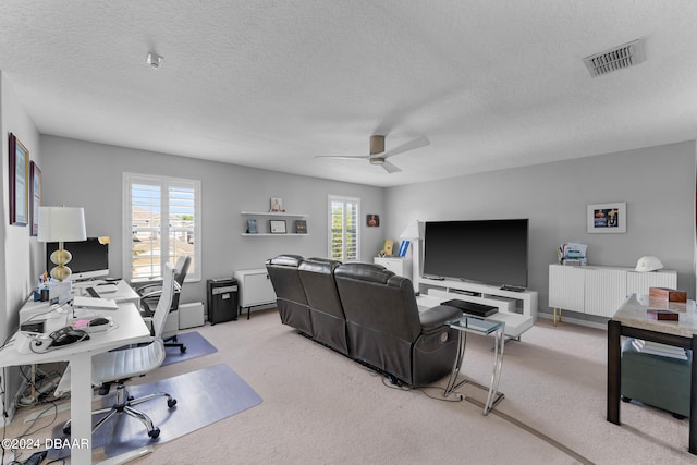 carpeted office featuring a textured ceiling and ceiling fan