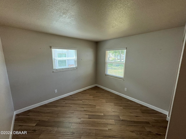 unfurnished room featuring dark wood-type flooring and a textured ceiling