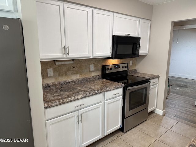 kitchen featuring light tile patterned floors, dark stone countertops, white cabinets, stainless steel appliances, and backsplash