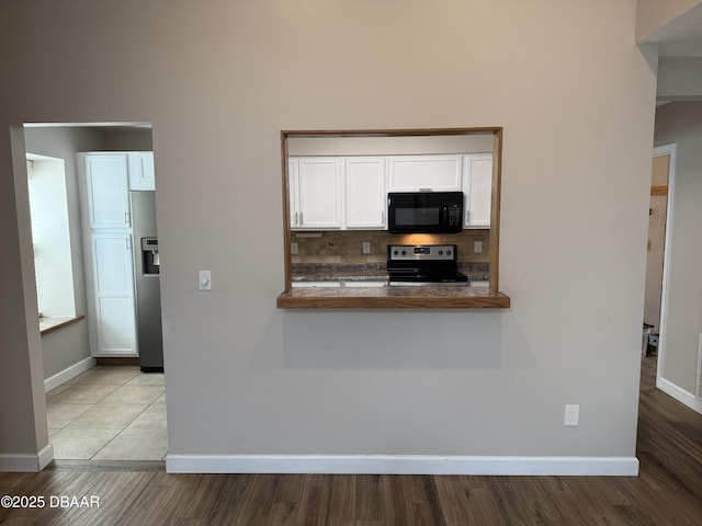 kitchen with white cabinets, light hardwood / wood-style flooring, decorative backsplash, kitchen peninsula, and stainless steel appliances